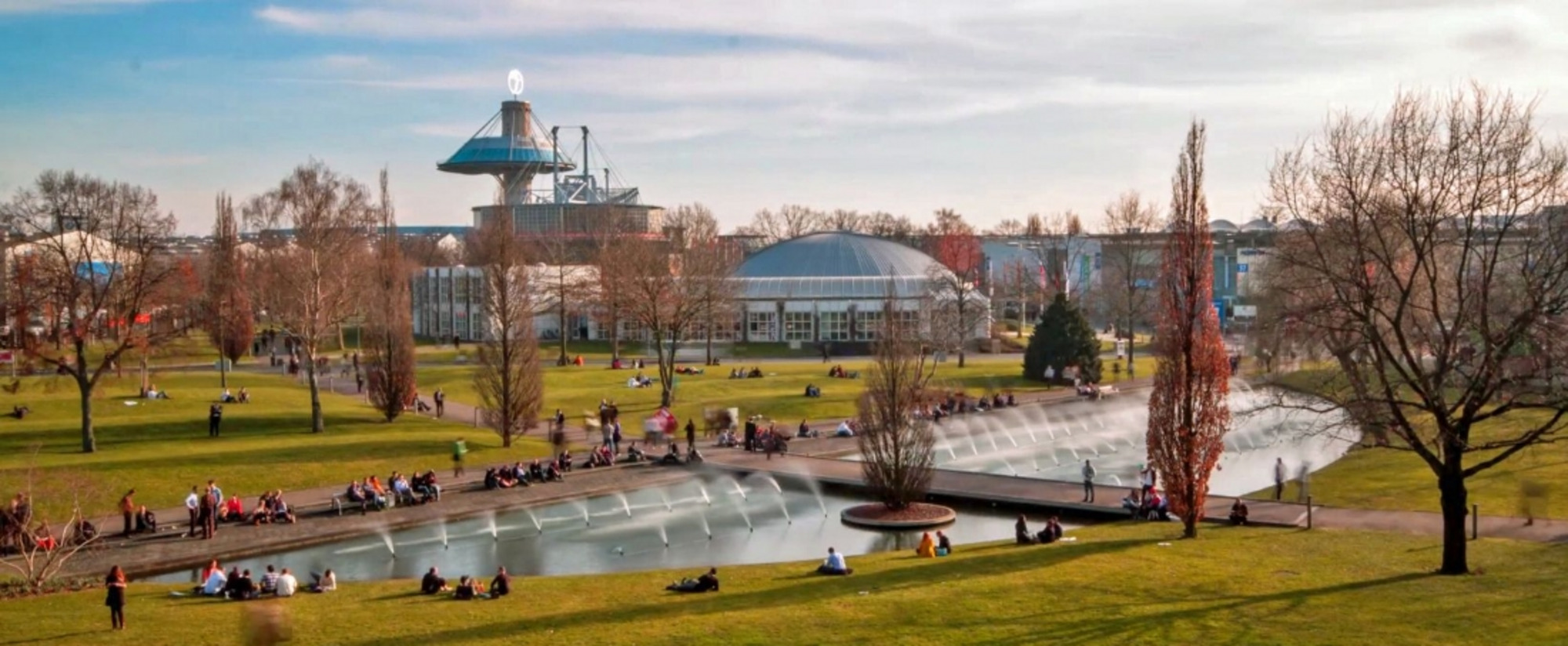 Messegelände Hannover mit Teich, Fontänen, moderner Architektur und Grünflächen im Sommerbetrieb.