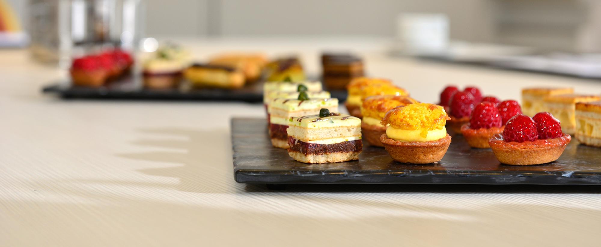 Zwei Schieferplatten mit einer Auswahl an Süßgebäck, Cupcakes und Törtchen - ordentlich angerichtet.