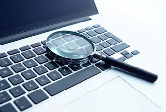 Lupe liegt auf Laptop-Tastatur – Symbol für digitale Suche oder Datenanalyse.