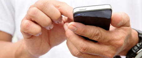 Hände halten ein Smartphone, eine Hand davon tippt auf dem Smartphone
